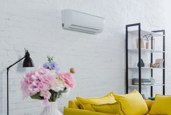interior of modern living room with flowers in vase, yellow couch and air conditioner hanging on