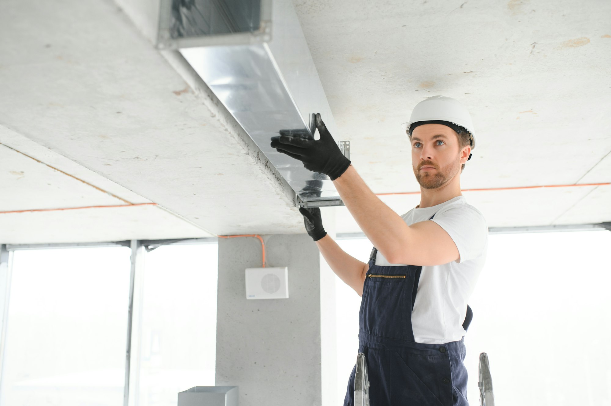 Warehouse Heating and Cooling System Installation by Professional Caucasian Technician.