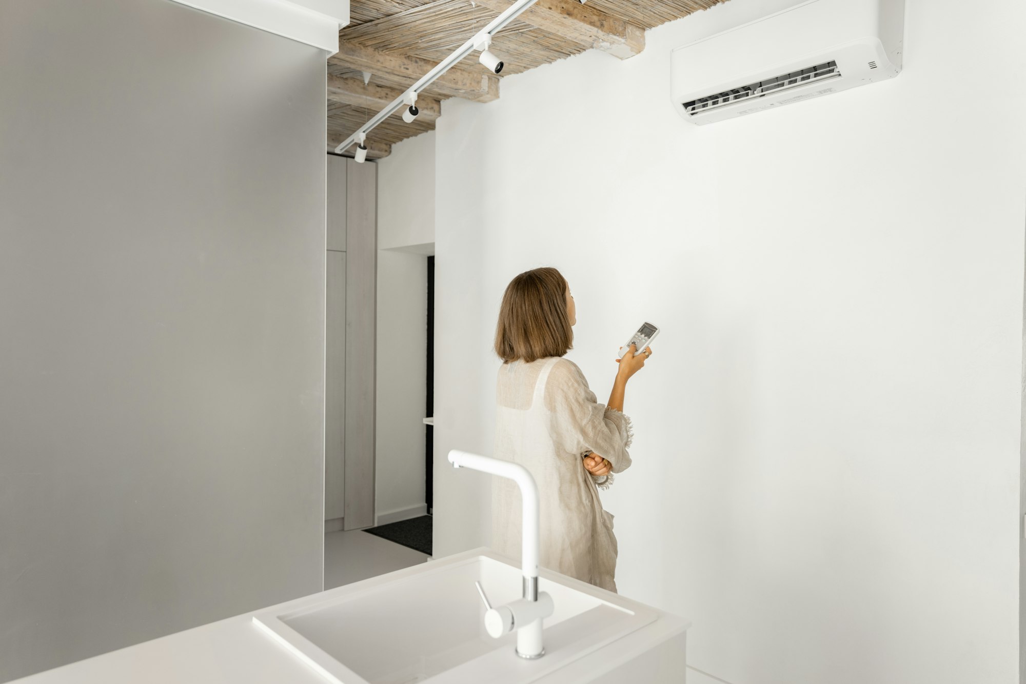 Woman sets the temperature on the air conditioner at home