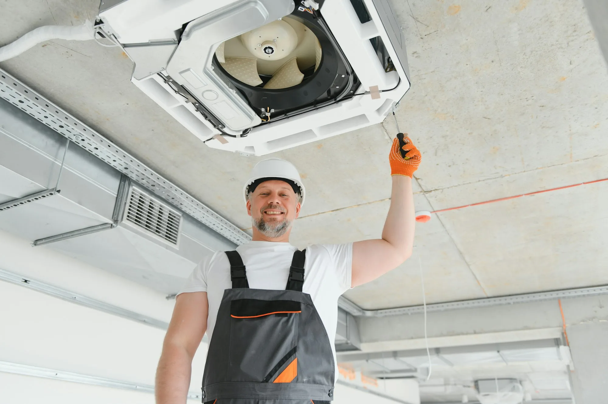 Worker repairing ceiling air conditioning unit