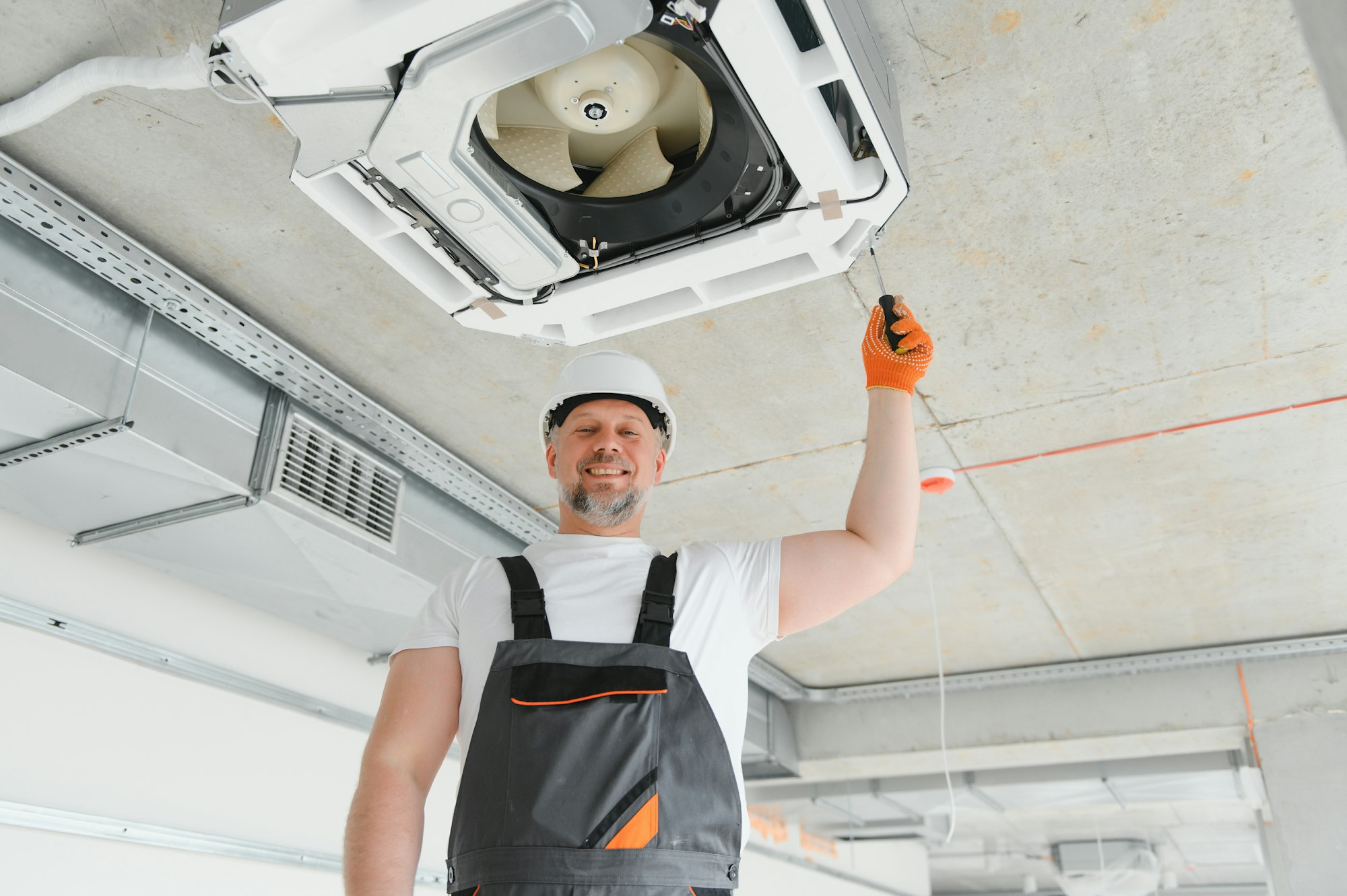 Worker repairing ceiling air conditioning unit